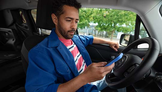A man using his smartphone to unlock a white Citroën C-Zero